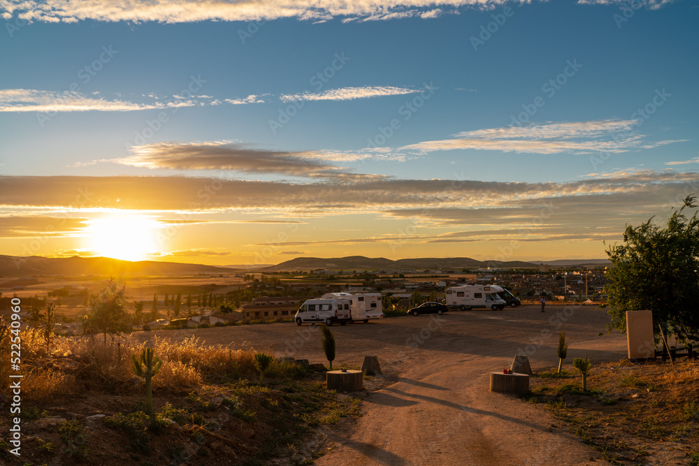 Beautiful and scenic sunset over a auto caravan parking. Golden hour warms colours and sun going down over the hills.