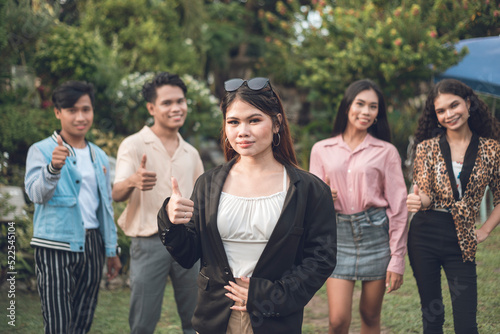 5 young friends or workmates including their leader giving a thumbs up sign, giving their approval. Outdoor scene. photo