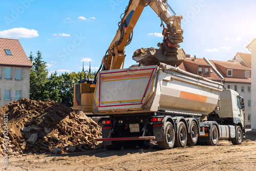 Obraz na plátně Heavy excavatore machine uploading waste and debris rubble into dump truck at construction site