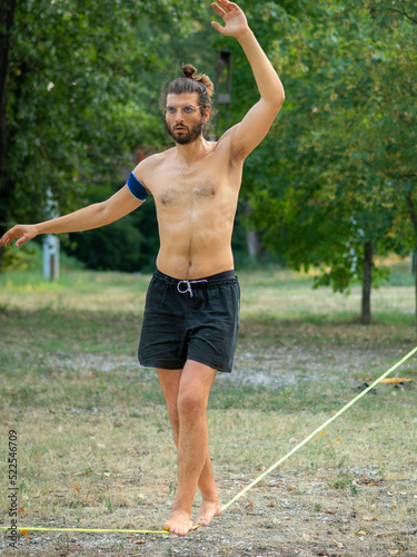fit young man training walking and balancing on slack line in a park