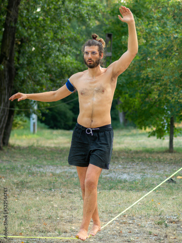 fit young man training walking and balancing on slack line in a park