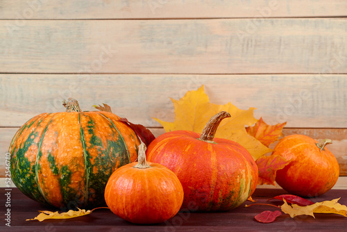 Autumn harvest. Ripe pumpkins and fallen leaves on wooden background. Thanksgiving and halloween concept.