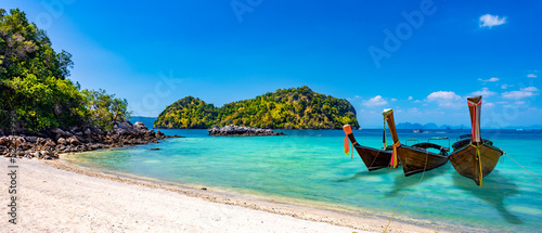 Three long tail boats await tourists on the beautiful islands and emerald crystal clear waters of Krabi, Thailand.