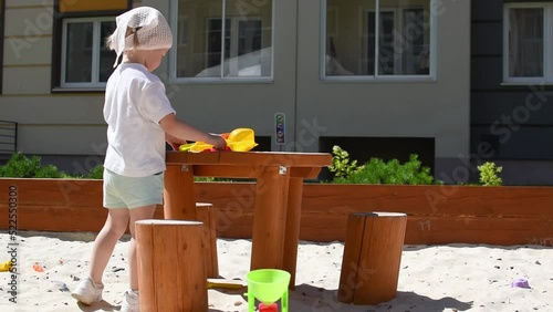 A girl is playing with shovels in the sandbox. High quality FullHD footage