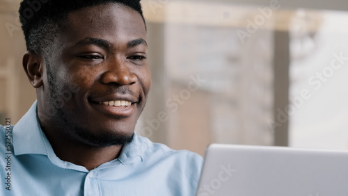 Thoughtful african american businessman writer dreamer genius man biracial guy holds hand on chin creates business plan come up with idea for startup uses computer typing text creates internet project