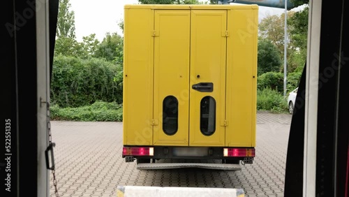 A yellow delivery van reverses and parks to load the truck with parcels photo