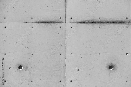 Concete wall of a building with wheathered facade. Traces like lines and dots from paving out the paneling. Architecture or construction site background with side light, black and white greyscale.