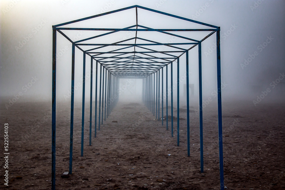 Seashore in winter in fog with metal structures and objects during the day Seashore in winter in fog with metal structures and objects during the day