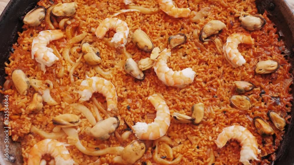 Cooking traditional Spanish Paella on a stove. Chef cooking food on fire from mussels, shrimp, squid rice, Catalan cuisine Cooking traditional Spanish Paella on a stove. Chef cooking food on fire from mussels, shrimp, squid rice, Catalan cuisine