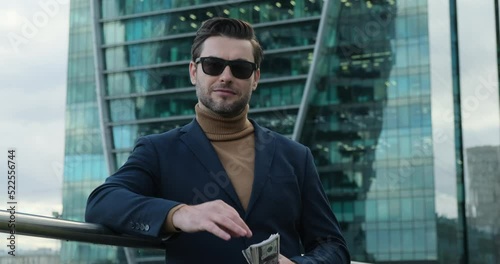 a successful businessman in a suit stands near a skyscraper and counts money. Successful business man counting money. american man checking bills, counting expences, examining credit balance photo