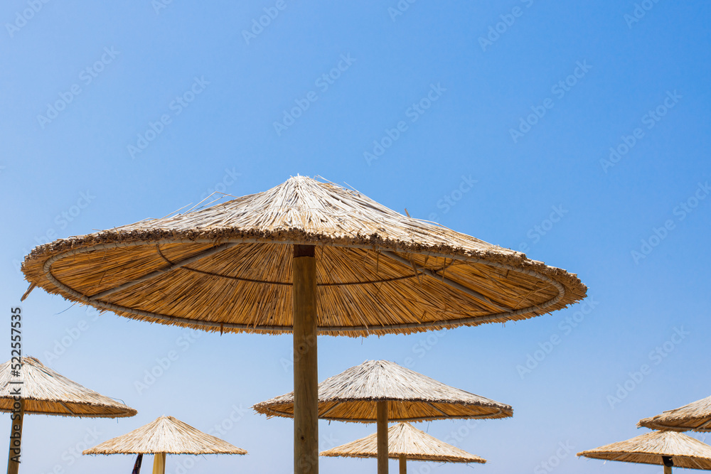 Bamboo parasols beach umbrellas with clear blue sky background on summer day