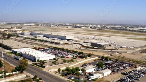 Aerial Shot Of Airplanes Parked At Airport In City, Drone Flying Forward On Sunny Day -  Ontario, California