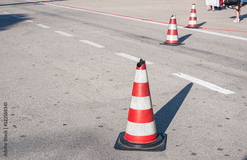 Traffic cones with white and red stripes on the road of the airport