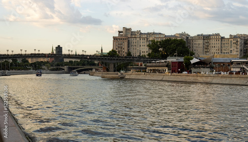 Photography Bridge with pedestrians across the Moscow River, pleasure boats and buildings and cars on the embankment