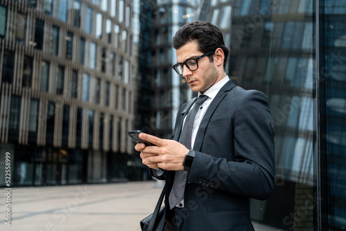 The manager is a man in a business suit going to work in the office, using an app on his phone