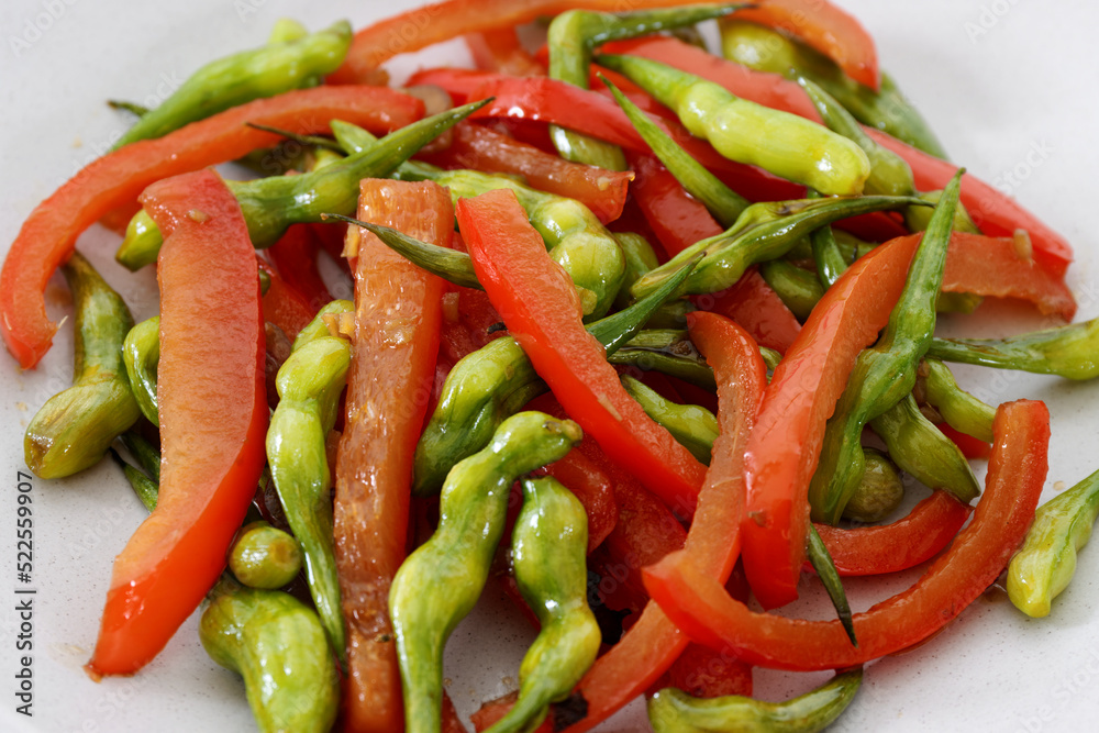 Stir-fry rat tail radish dish with red bell pepper on a plate. Vegan cuisine meal. Stir-fry rat tail radish dish with red bell pepper on a plate. Vegan cuisine meal.