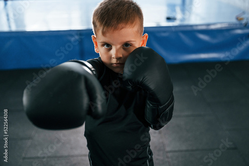 Boy is practicing boxing in the gym with glowes on hands