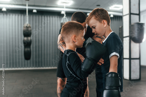 Preparing for the sparring. Young tattooed coach teaching the kids boxing techniques