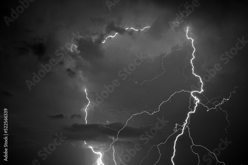 Fork lightning striking down during summer storm in black and white