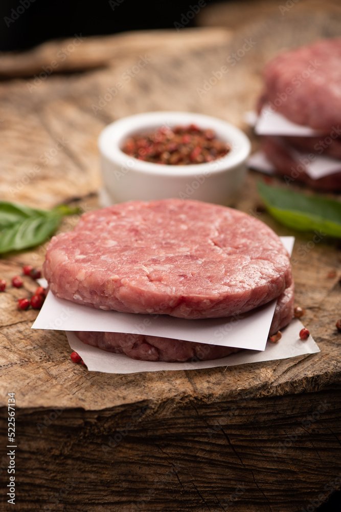 Raw beef meat burger steak cutlets and dry red pepper wooden background