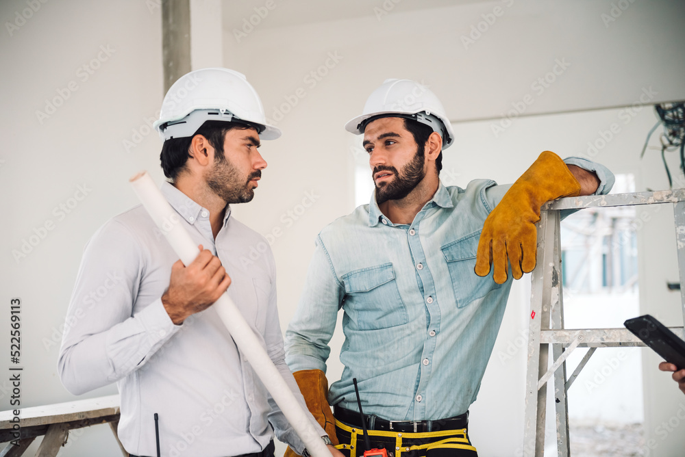Portrait of two caucasian man construction worker and project manager wearing hardhat and safety equipment working together at construction site. Real estate industry. Portrait of two caucasian man construction worker and project manager wearing hardhat and safety equipment working together at construction site. Real estate industry.