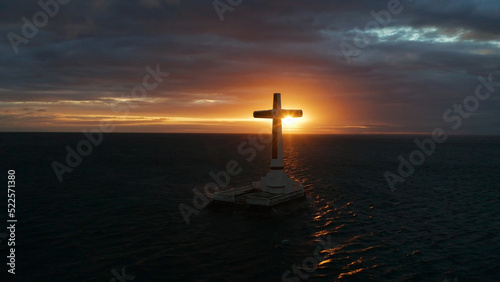 Catholic cross in sunken cemetery in the sea at sunset, aerial view. Colorful bright clouds during sunset over the sea. Sunset at Sunken Cemetery Camiguin Island Philippines.