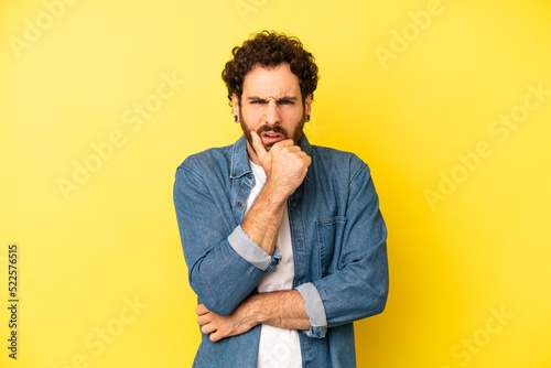 Fototapeta young bearded man with mouth and eyes wide open and hand on chin, feeling unplea