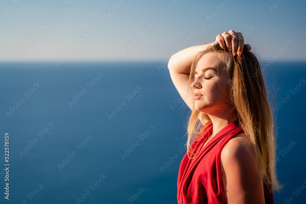 A woman in a red flying dress fluttering in the wind, against the backdrop of the sea. A woman in a red flying dress fluttering in the wind, against the backdrop of the sea.