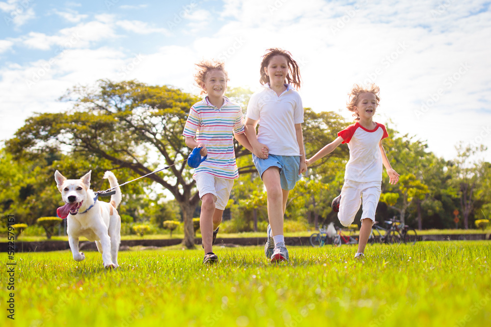 Obraz premium Kids play with dog. Children and puppy run in park