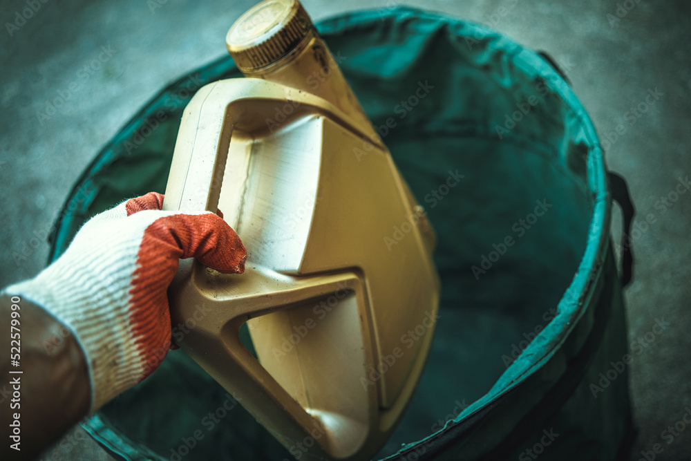 A gloved hand throws out a canister from under the oil for the car. Disposal of oil waste. A