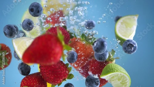 Super slow motion shot of fruit falling into the water with splashing. Blue background.
