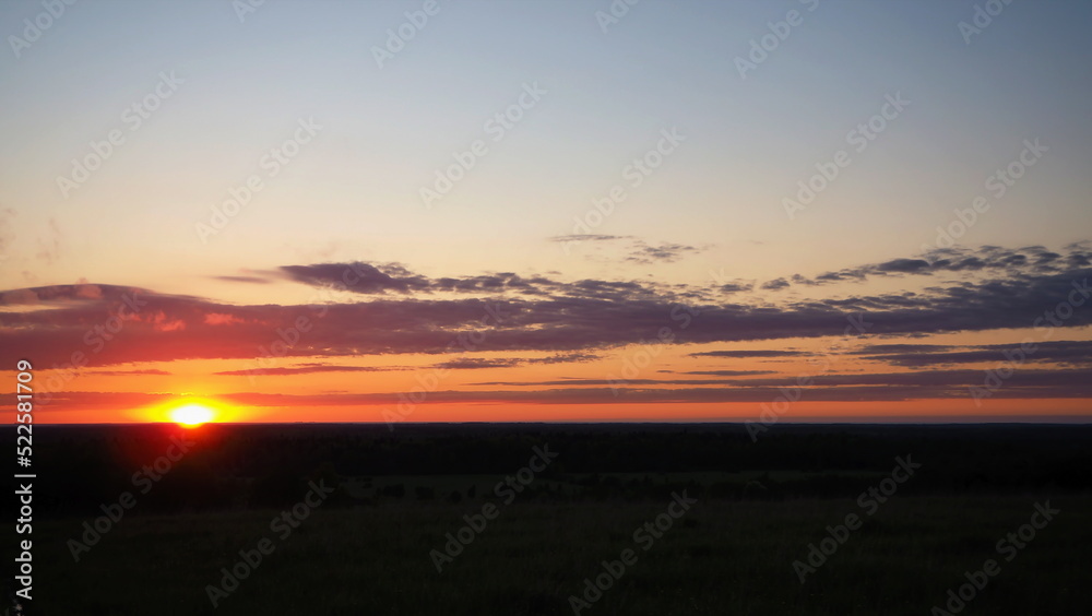 Rural landscape. A beautiful sunset on a hill and a forest stretching to the horizon. Leningrad region, Russia.