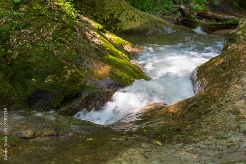 Fototapeta Naklejka Na Ścianę i Meble -  A mountain river in a natural channel with rapids and waterfalls.