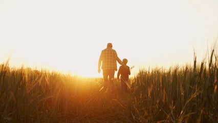 Farmer and his son in front of a sunset agricultural landscape. Man and a boy in a countryside field. Fatherhood, country life, farming and country lifestyle.