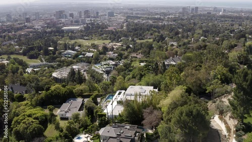 Aerial Shot Of Bel Air Mansion Amidst Trees On Hill, Drone Flying Forward During Sunny Day -  Los Angeles, California photo