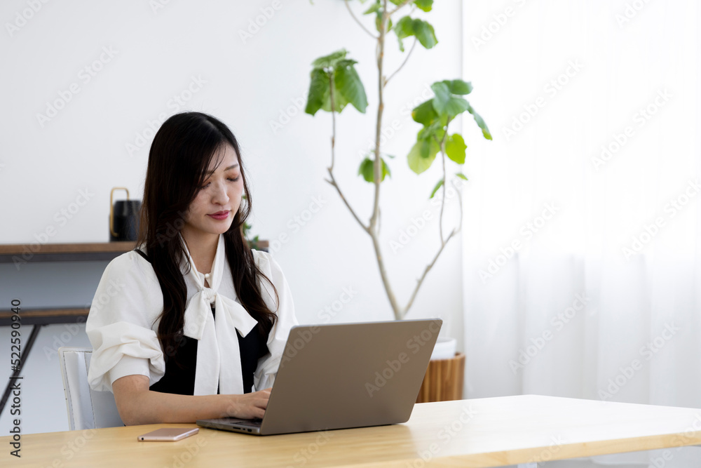A working Japanese woman by remote work in the home office closeup
