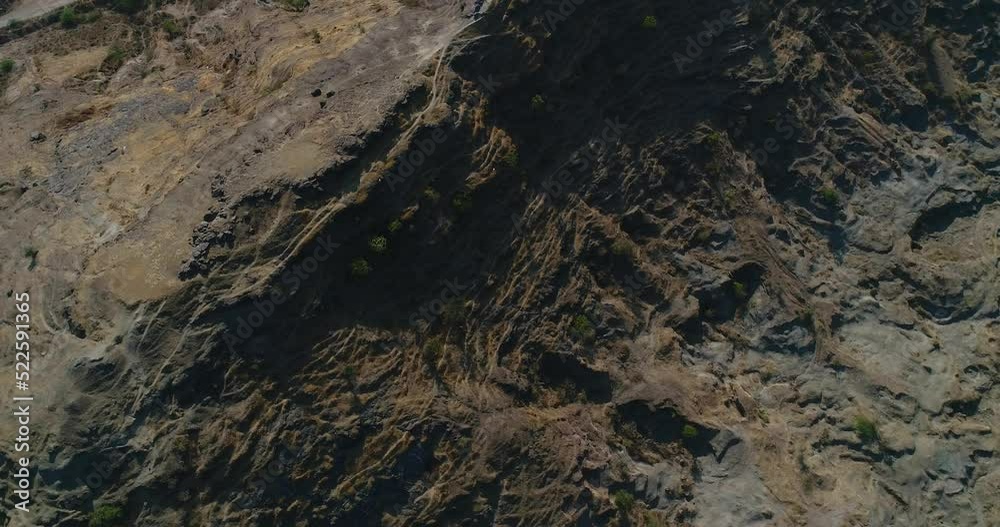 Aerial shot of steep side of rocky hill with plateau on top, city below Aerial shot of steep side of rocky hill with plateau on top, city below