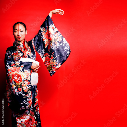 Fotografia young pretty geisha on red background posing in kimono, oriental