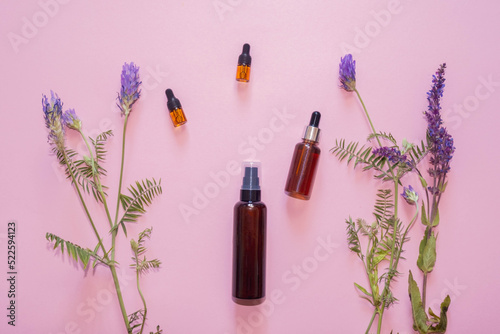 Flat lay composition with lavender flowers and natural cosmetics on a pink background.