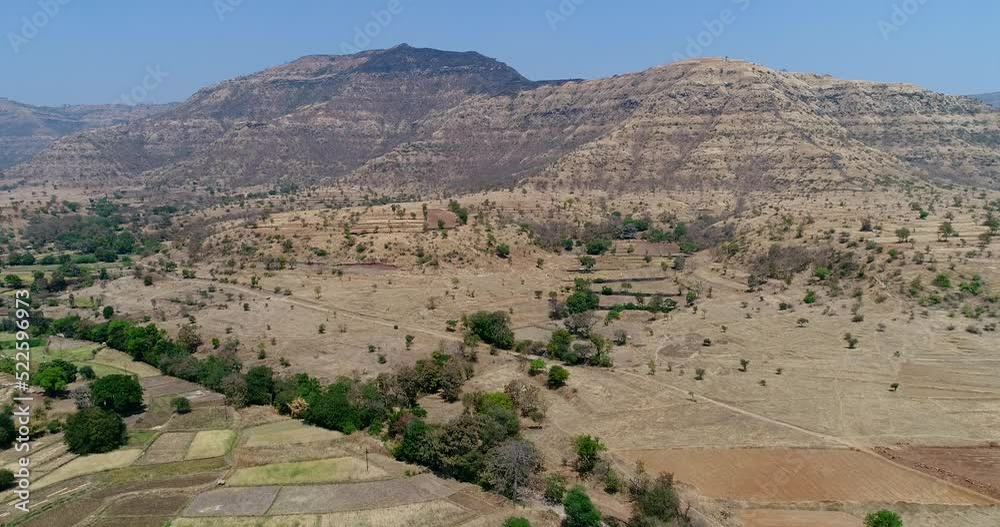 Aerial shot of steep rocky dry hills, fields and trees at bottom Aerial shot of steep rocky dry hills, fields and trees at bottom