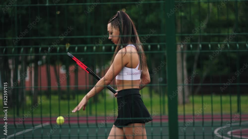 sexy brunette woman is walking on tennis court and hitting ball, sport training and active lifestyle