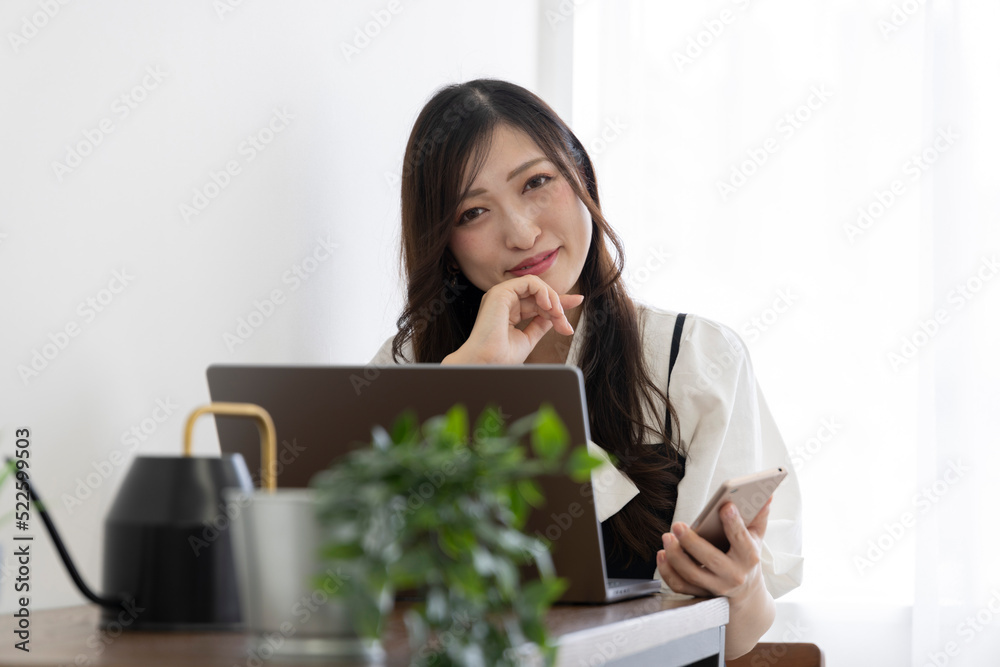 A Japanese woman checking smartphone by remote work in the small office A Japanese woman checking smartphone by remote work in the small office