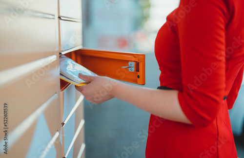 Woman picks up mail from automated self-service post terminal machine. photo