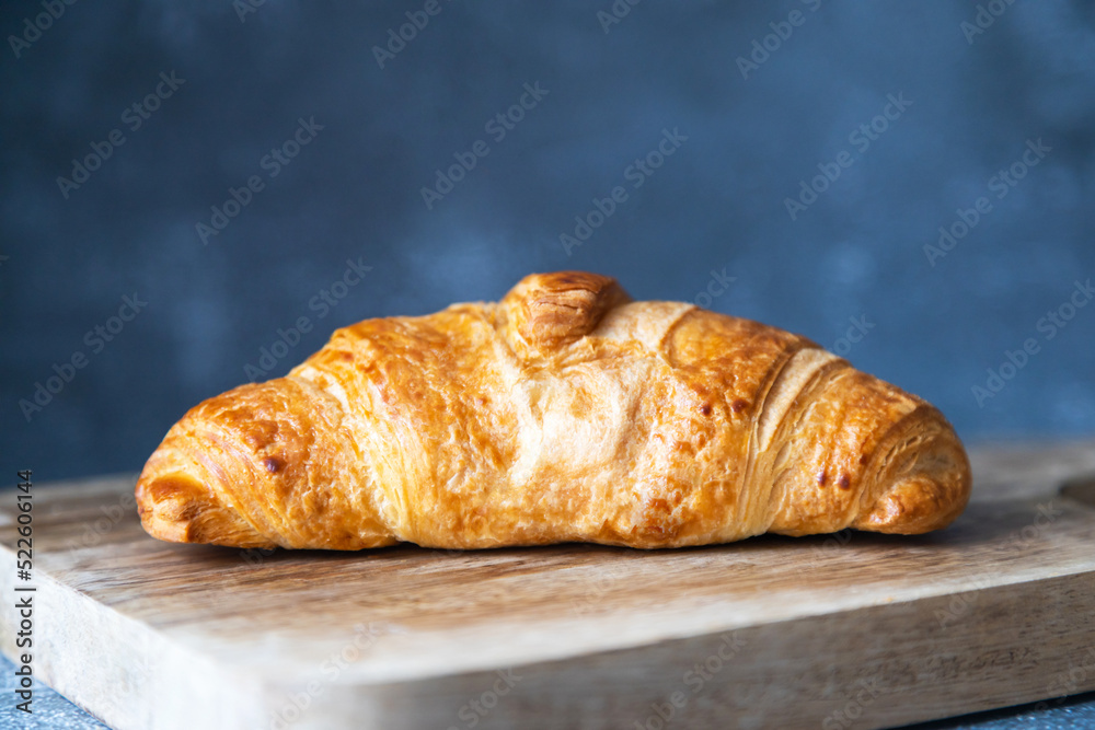 Fresh and juicy croissant on a cutting board on a dark background. Place for text. Fresh bakery
