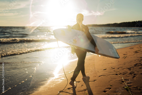 Canvas Print A male surfer on a surfboard wetsuit goes to play sports in the sea
