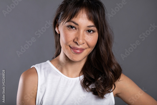 Close-up attractive happy asian smiling woman posing in studio on gray