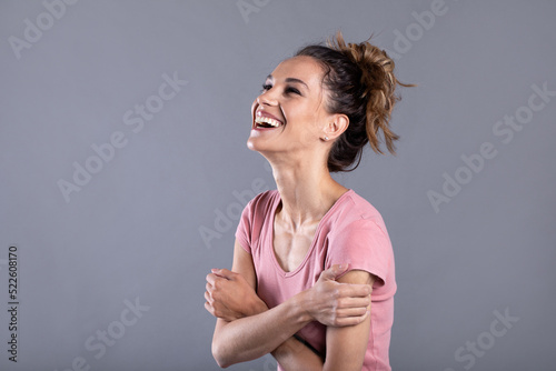 Cheerful stylish woman posing at studio on gray