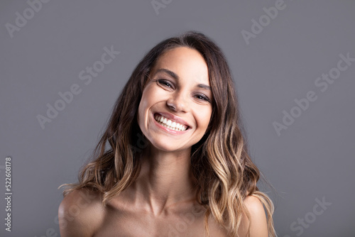 Close-up attractive girl smiling on gray isolated background.