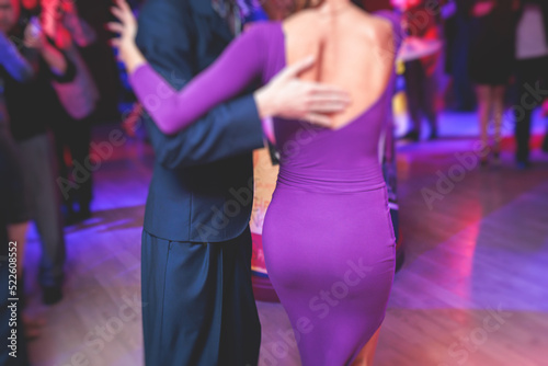 Couples dancing traditional latin argentinian dance milonga in the ballroom, tango salsa bachata kizomba lesson in the red and purple lights, dance festival