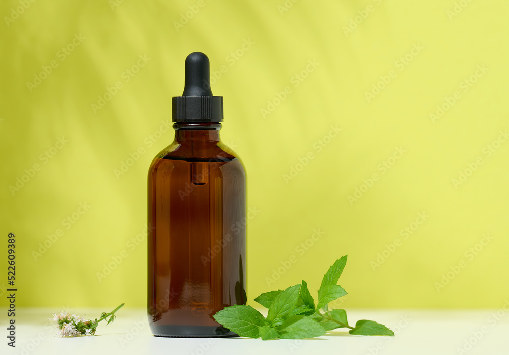 A brown glass bottle with a pipette on a green background. Containers for cosmetics A brown glass bottle with a pipette on a green background. Containers for cosmetics
